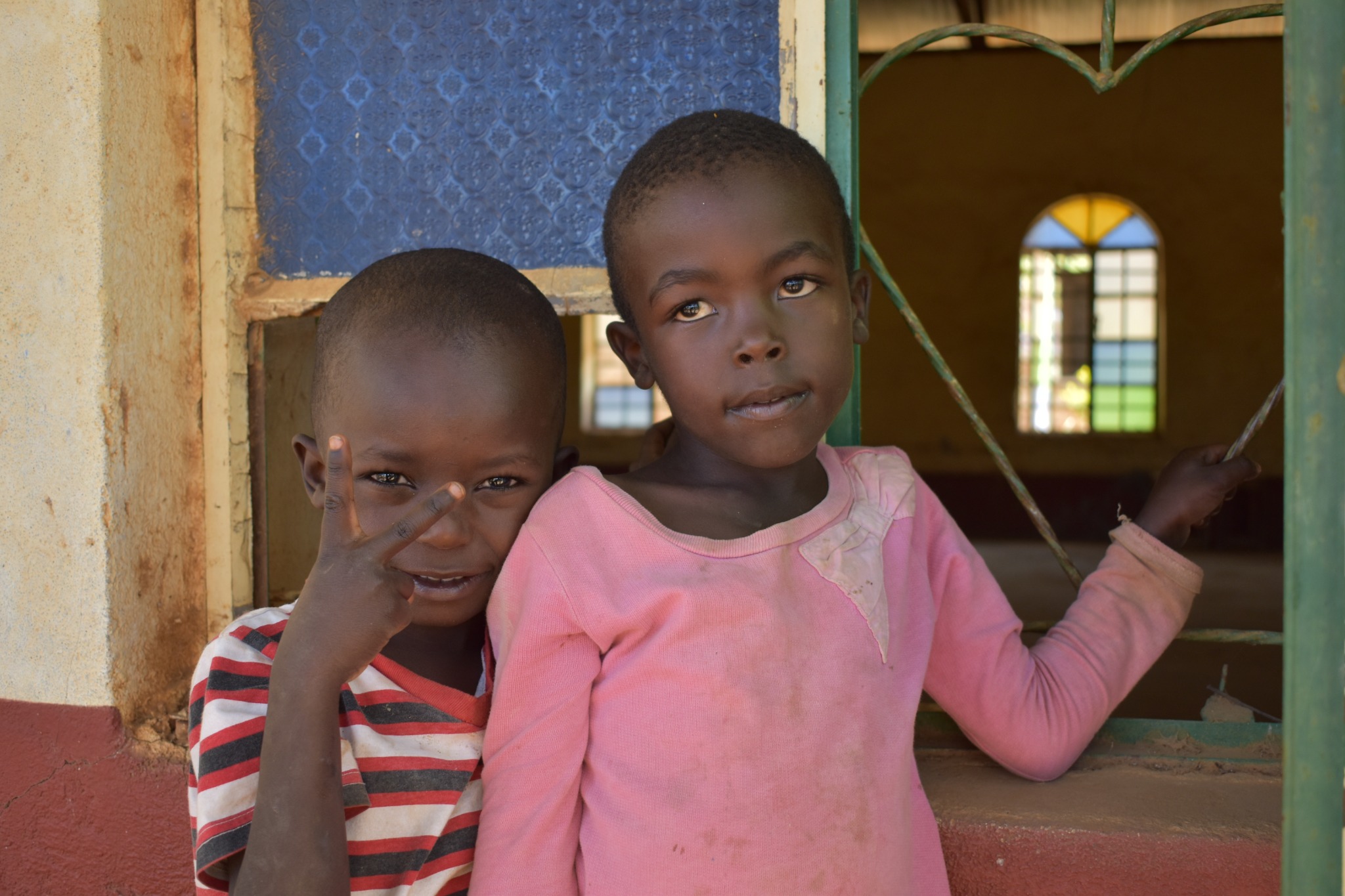 Two children standing by a window